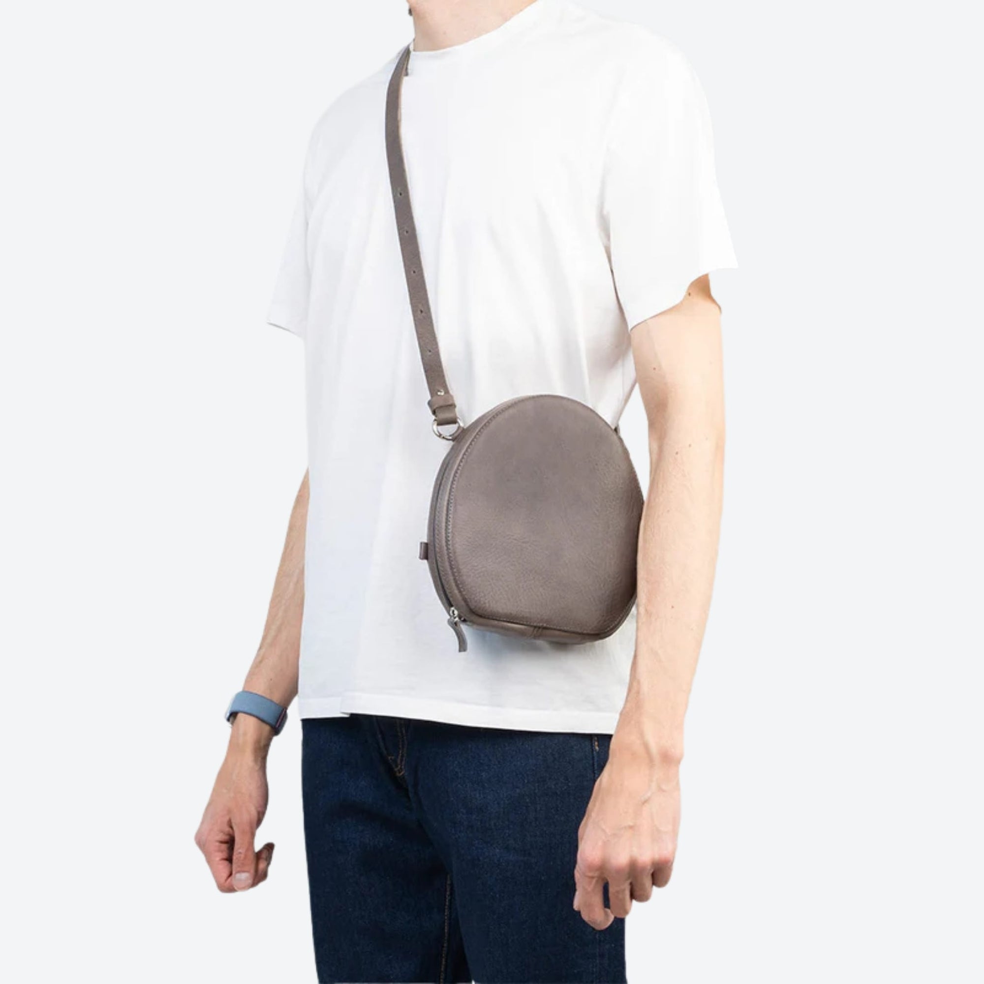 Person wearing a gray crossbody bag on a white background
