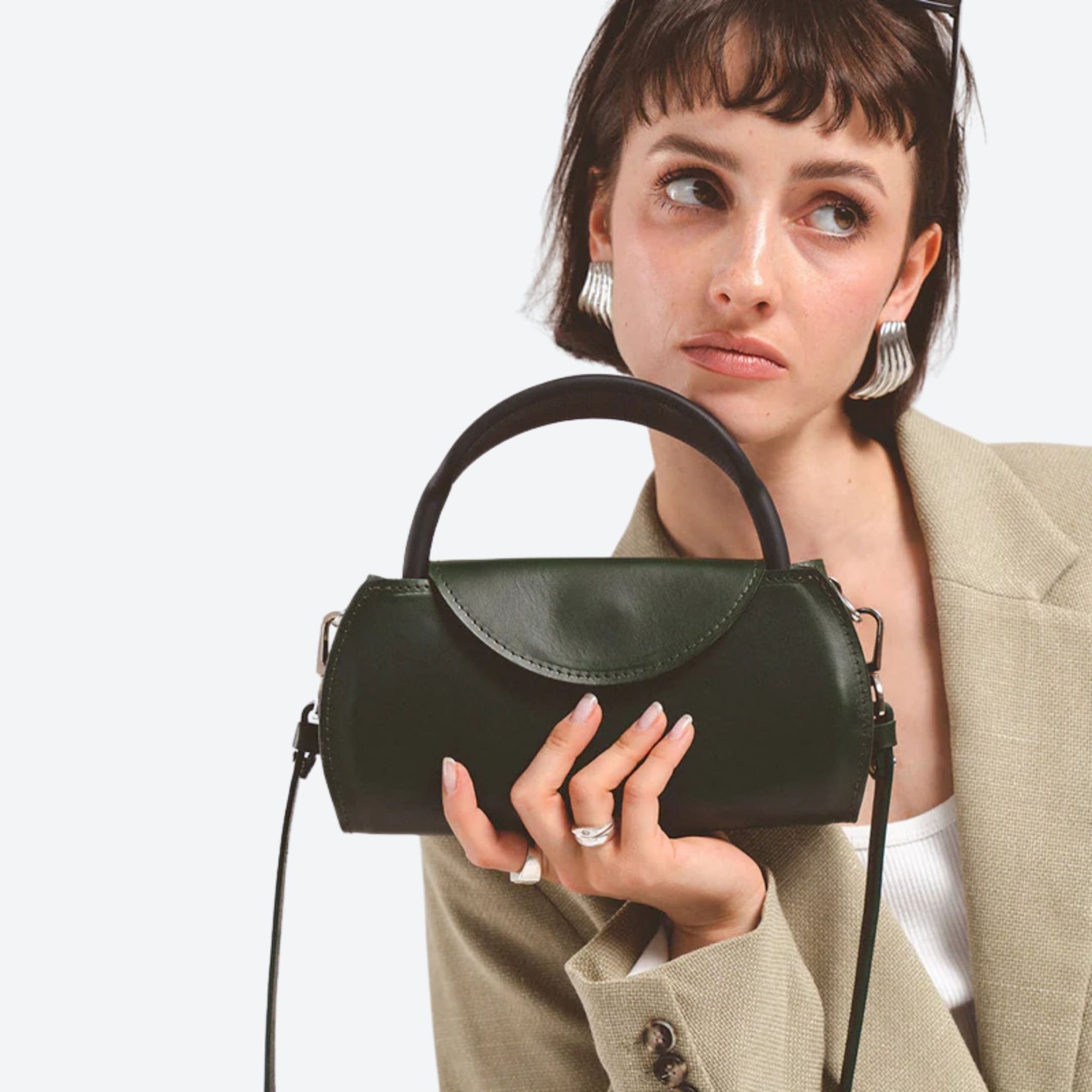 Woman holding a black handbag against a plain background