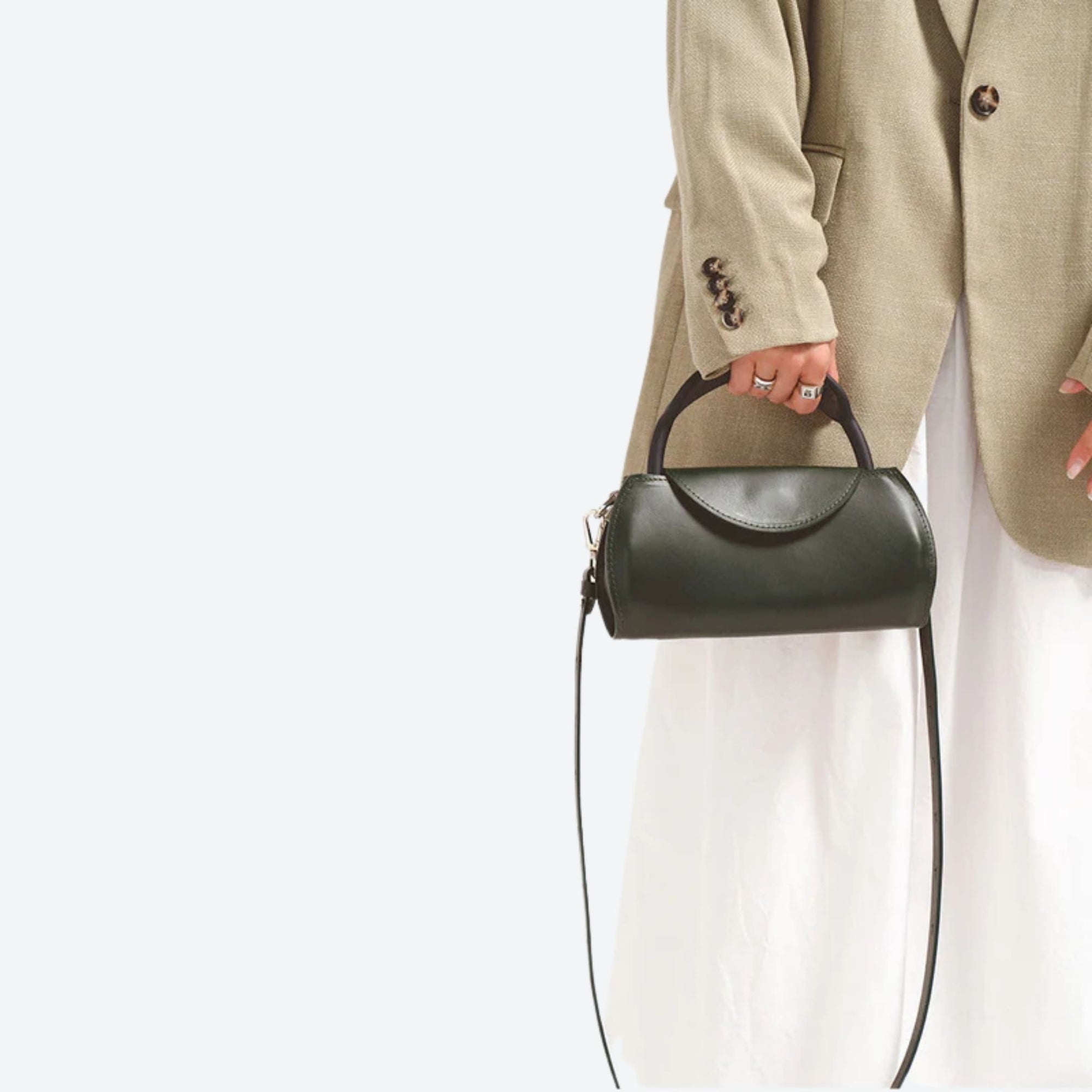 Person holding a black handbag against a white background
