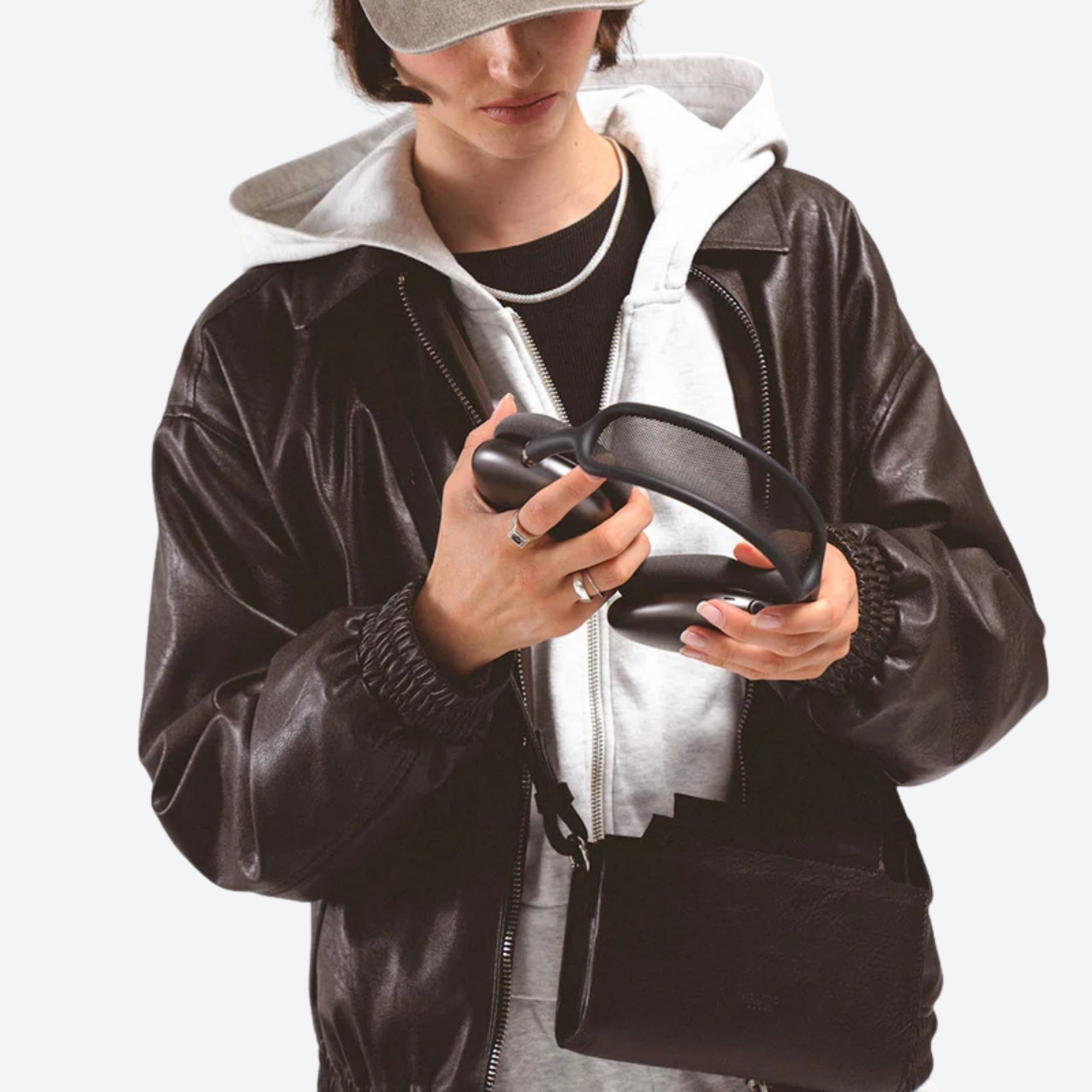 Person wearing a black leather jacket holding a black object against a white background