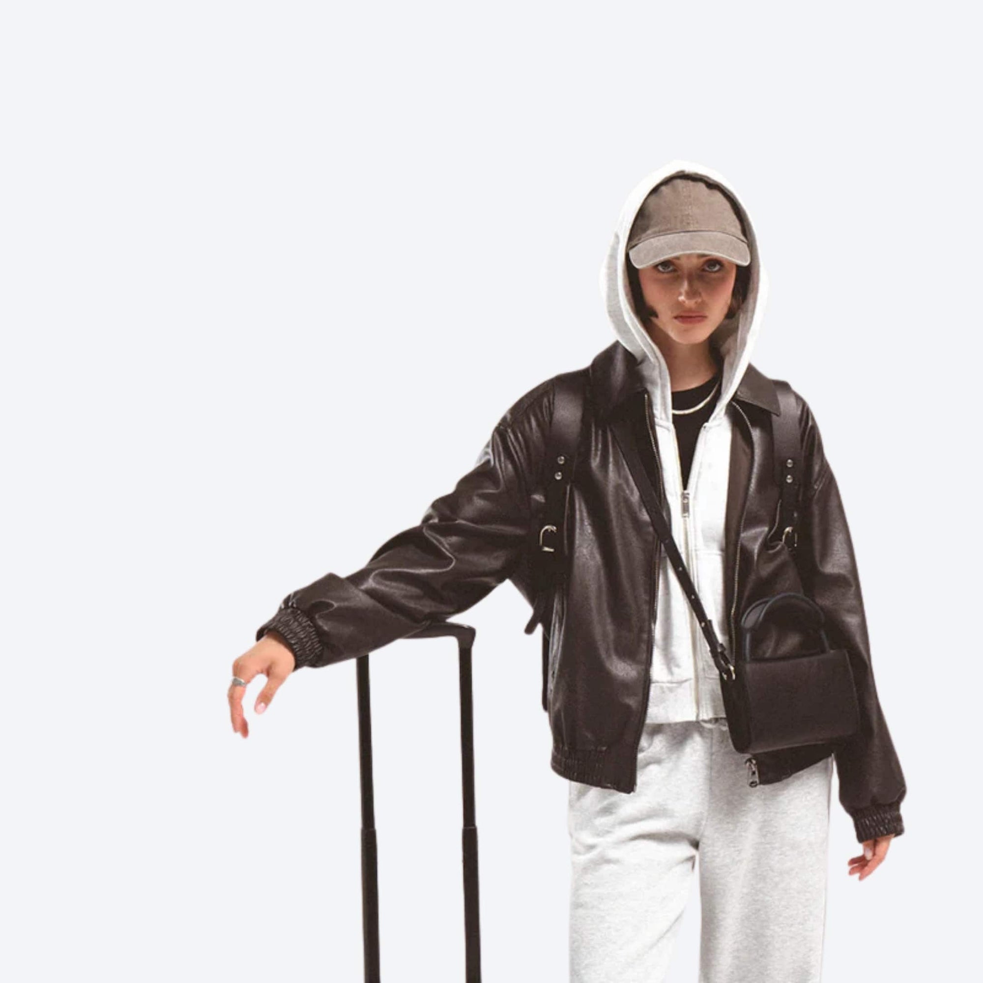 Person wearing a brown leather jacket and white hoodie with a neutral background